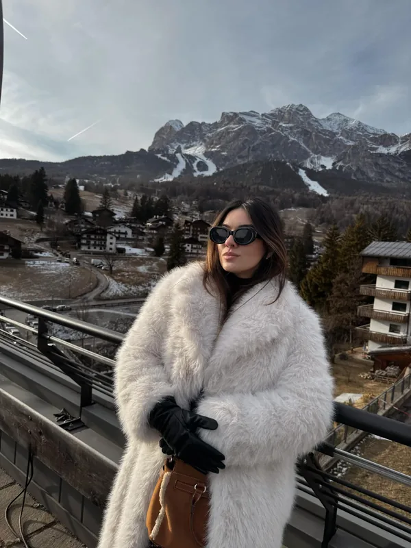 Carol Marcelino diante de uma paisagem de montanhas nevadas na Europa.