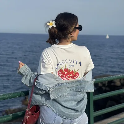 Look com jeans e pontos de cor à beira-mar.